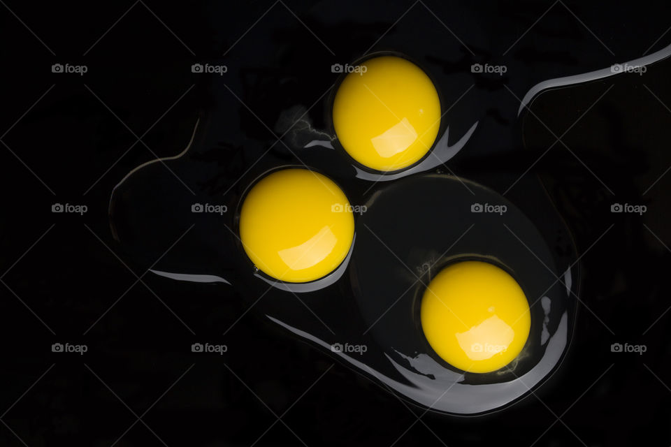 three yellow yolks on black background.  The three concept.