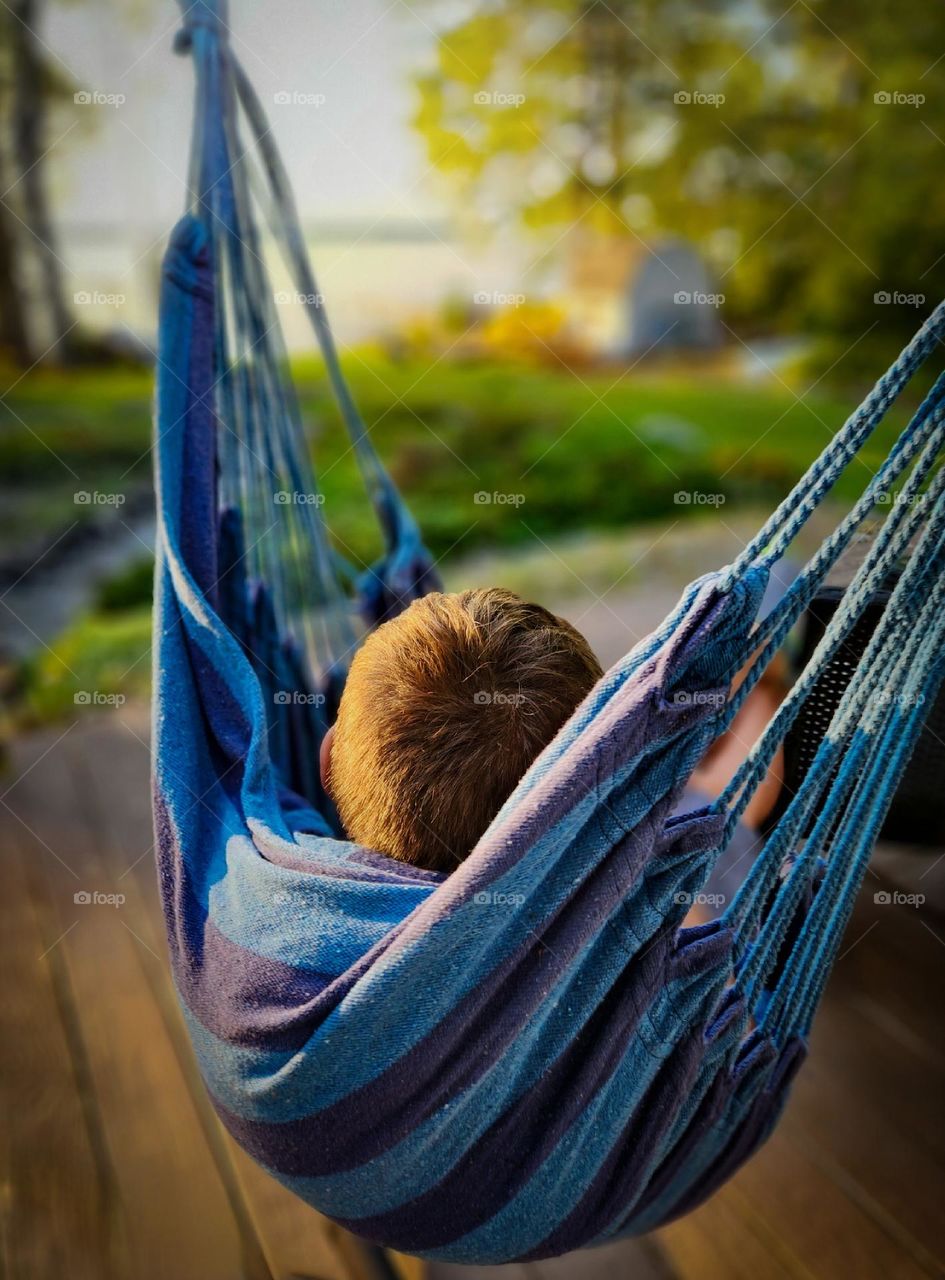 Boy in blue swing gazing at the sunset