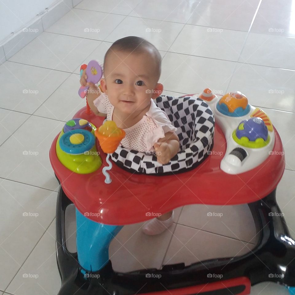 baby having fune while she playing on her walker.