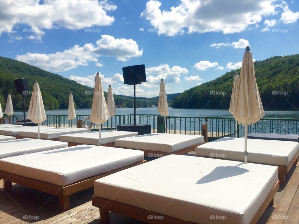 White sunbeds with white umbrellas near the lake