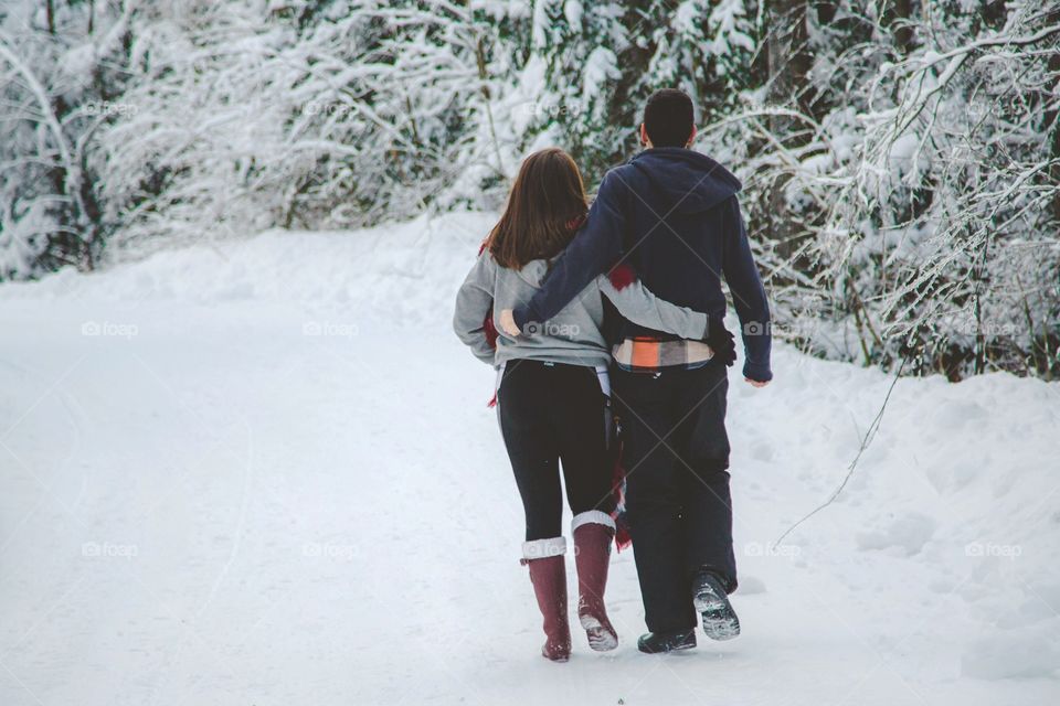 A couple walking and bonding through a forest of large pines