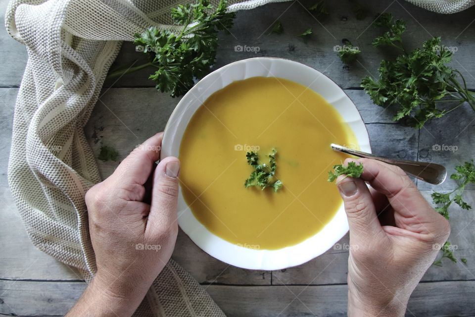 Man adding fresh parsley to bowl of butternut squash soup