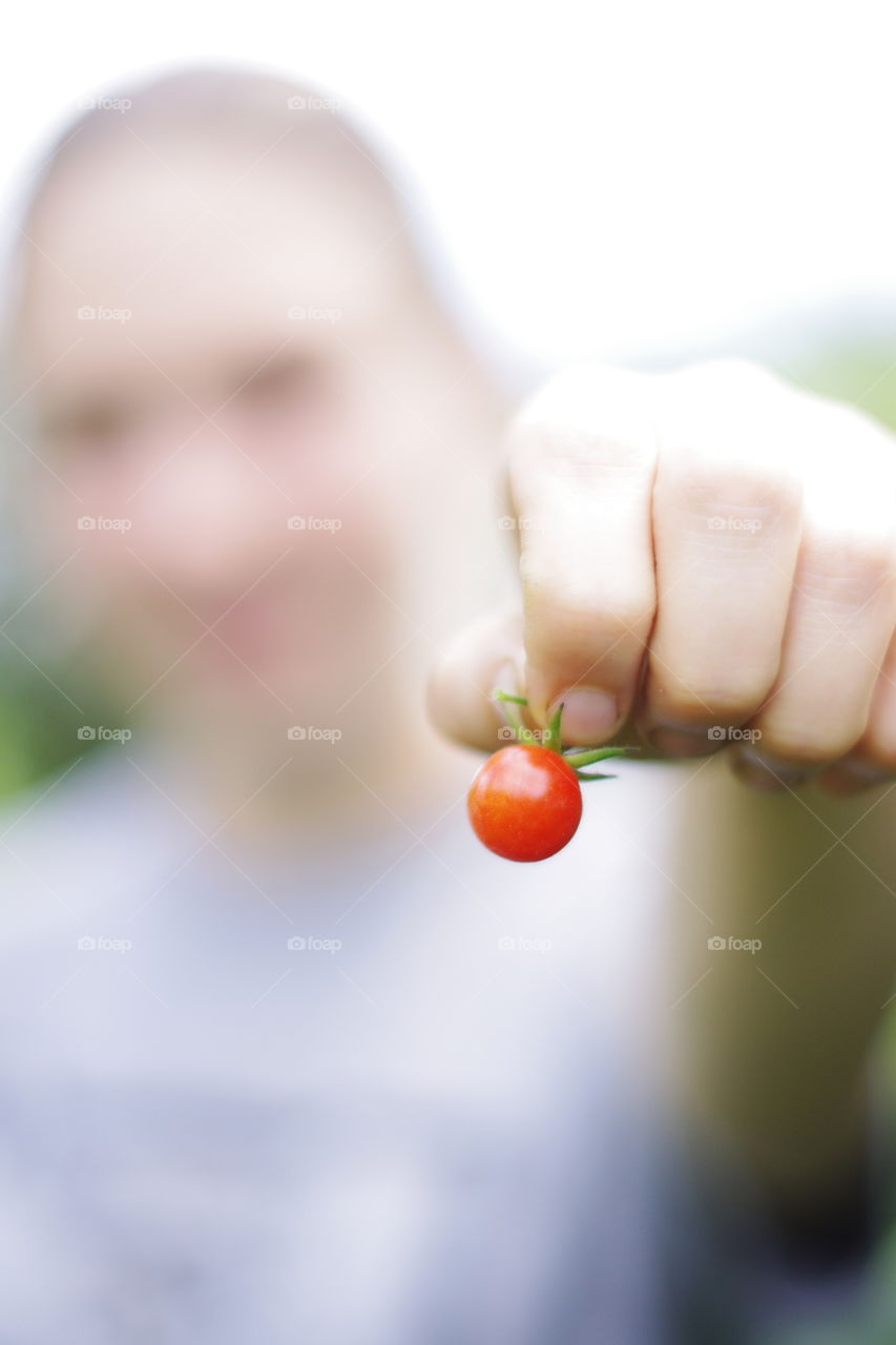 A person holding cherry tomato in hand