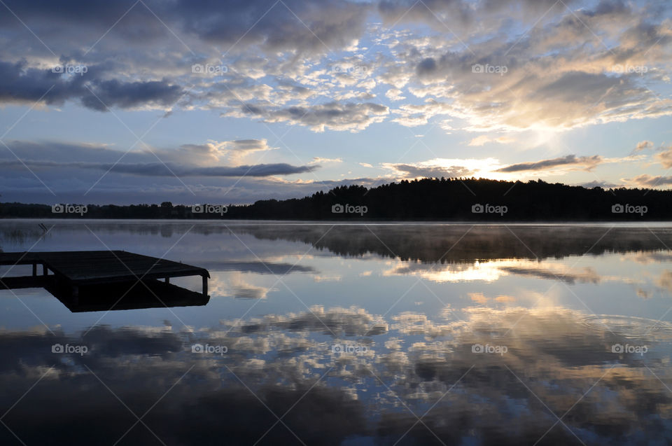 pier and forest silhouette at the lakeside during sunrise