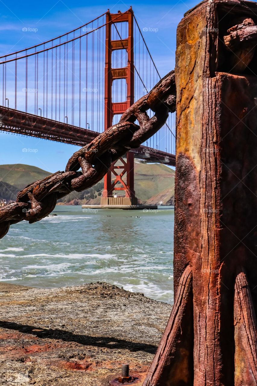 Looking at the Golden Gate Bridge through the rustic iron chain link guard rails with all their beautiful aged patina on a beautiful sunny day at Fort Point 