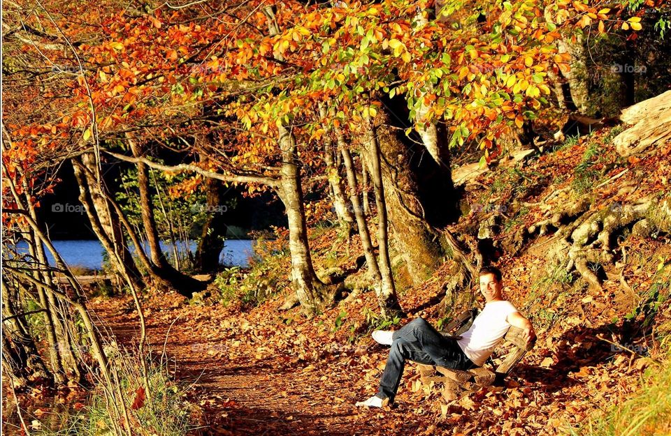 Happy man enjoying autumn! :). Happy man enjoying autumn on a bench surrounded by colorful trees