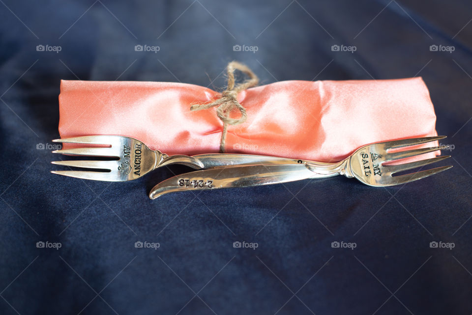 Two forks on blue table with pink tiied napkin