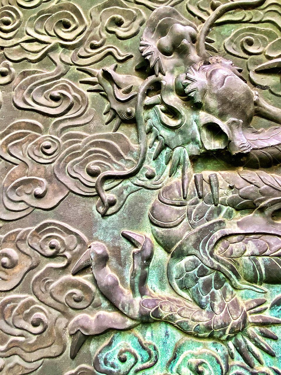 Historical ornate sculpture of dragon and swirling clouds on face of bronze door.  