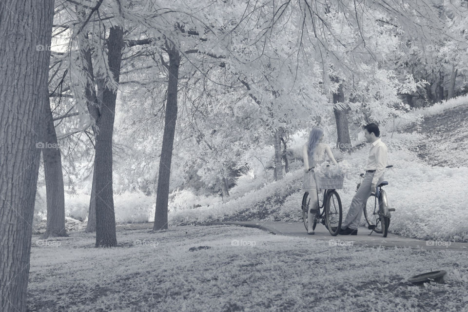 A ride in the park. A young couple take a pause to chat and flirt while on bike ride in the park