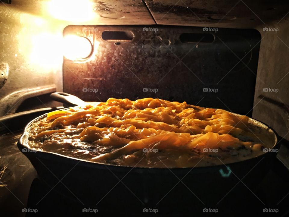 Quiche in the oven with unmelted cheese on top.