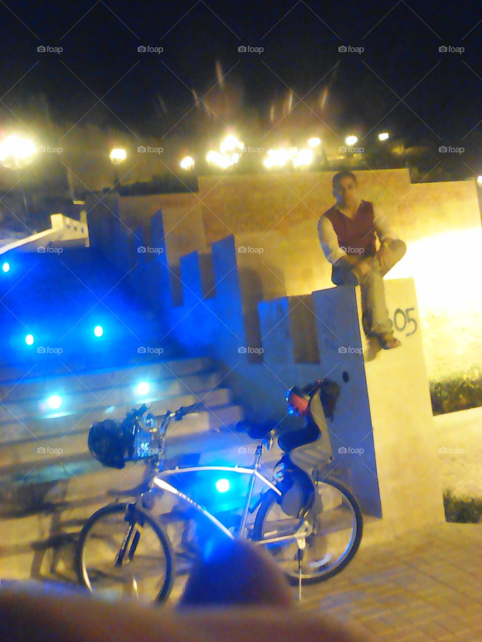 Indian man sitting on staircase near illuminated bicycle