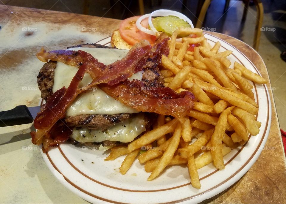 huge cheeseburger with Swiss cheese and bacon and a side of fries