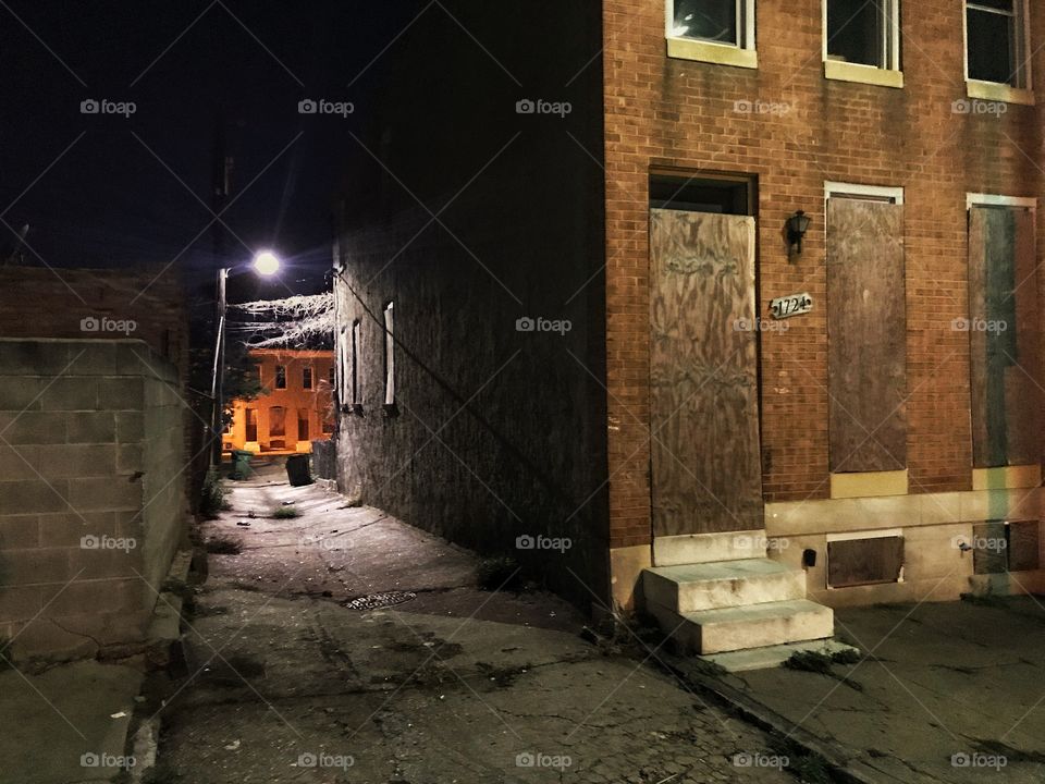 Dark creepy alley with boarded up abandoned building in foreground 