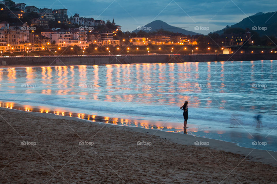 Woman standing on beach at sunset
