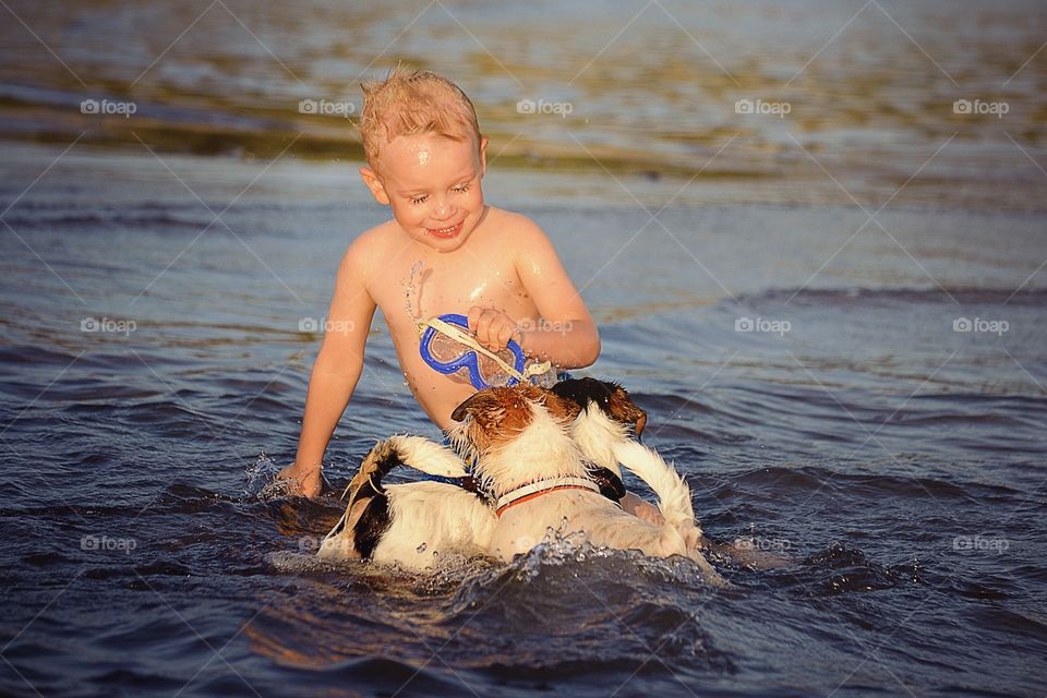 Happy. Boy playing with dogs at the beach