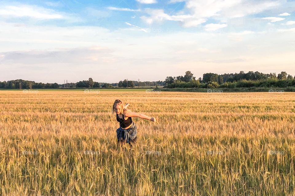 Girl walking in a field of wheat 