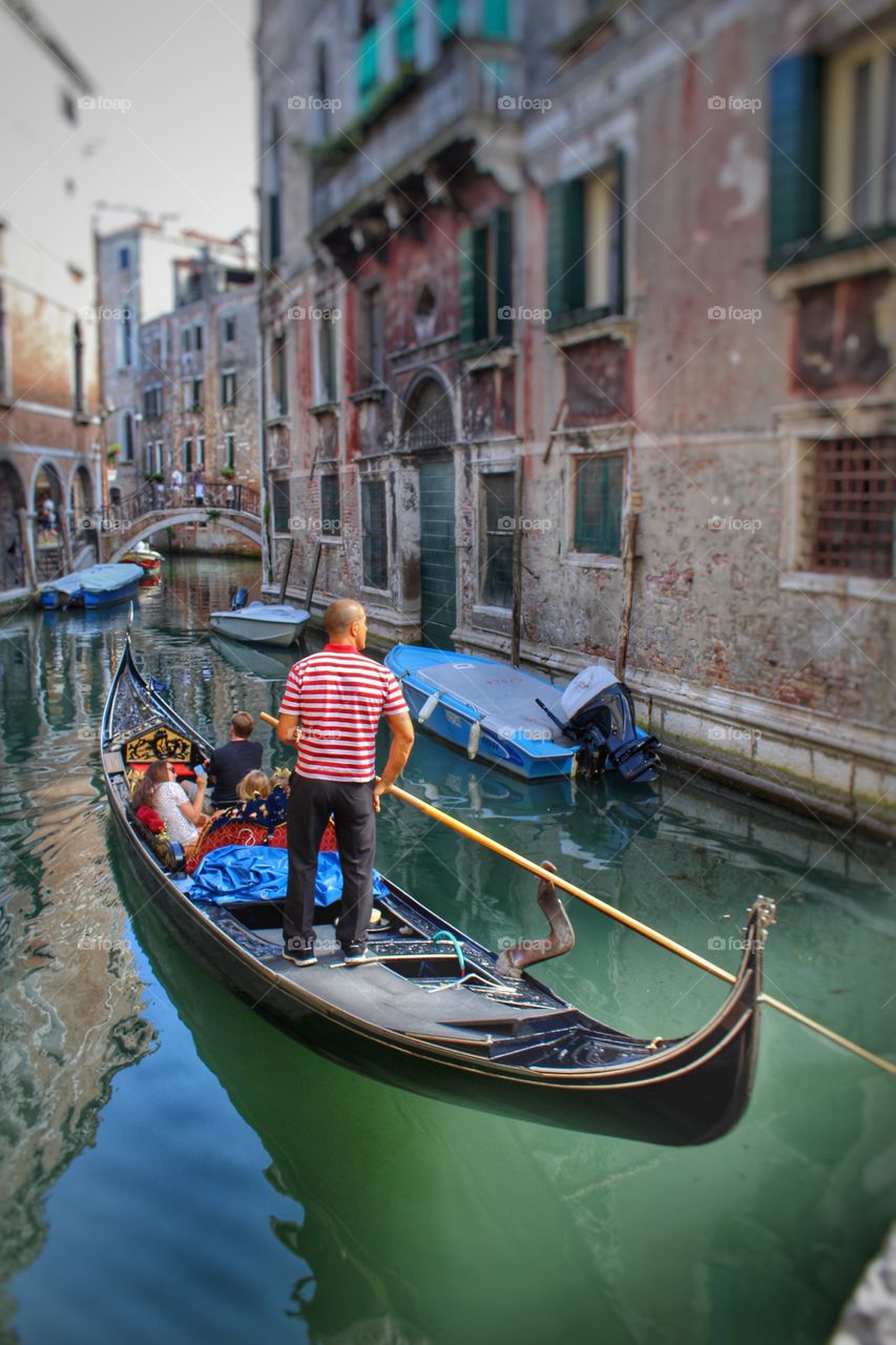 A gondolier steers his passengers through canals in Venice