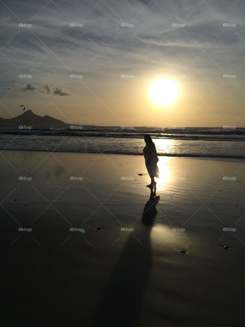 A sunset silhouette shot in a calm and peaceful beach with a pastel sky overhead.