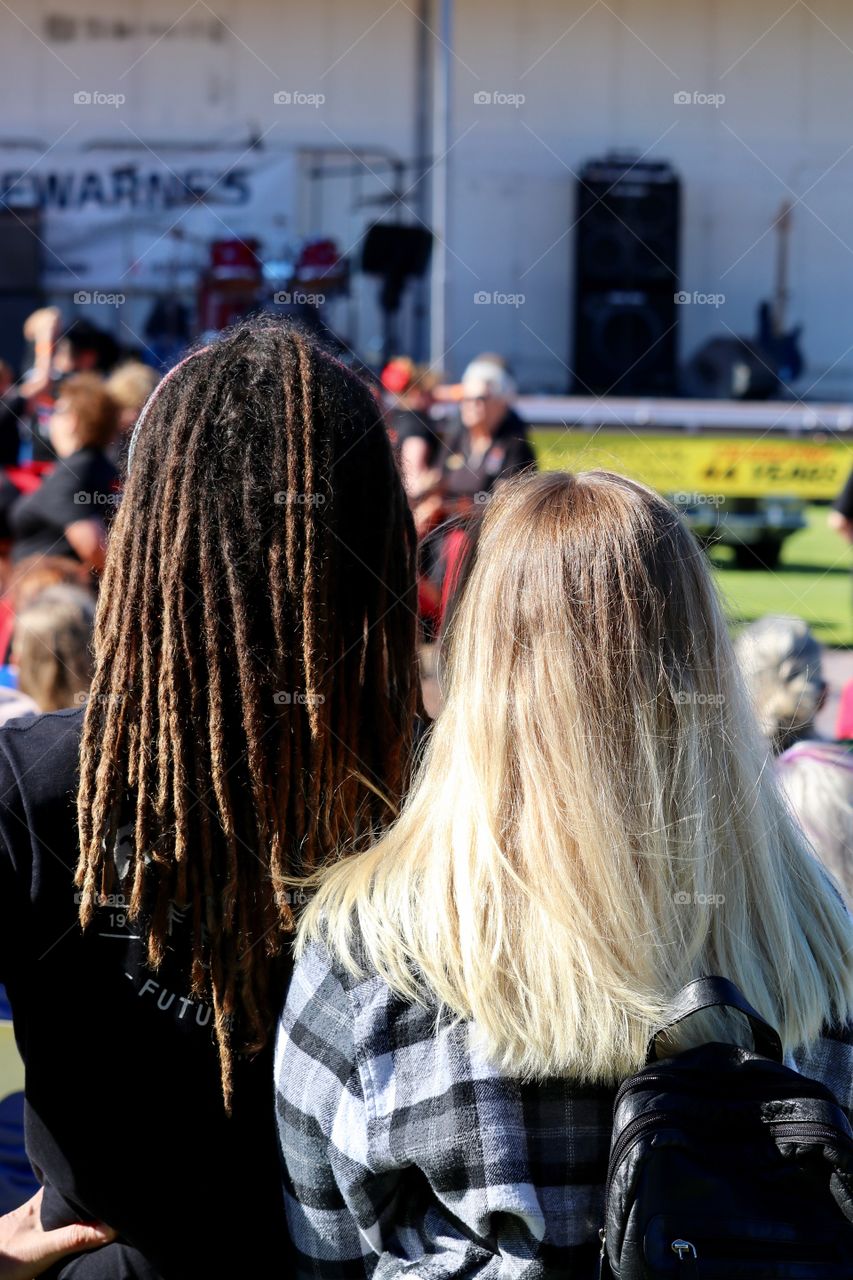 Dreadlocks and long hair, make female couple at festival, back of head shots