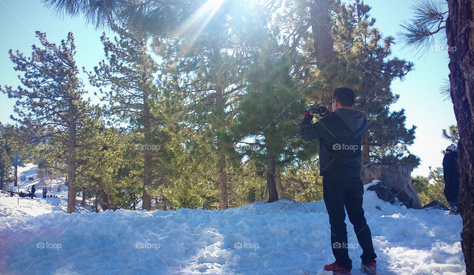 winter story, man taking a photo of rhe snow view, using mobile phone
