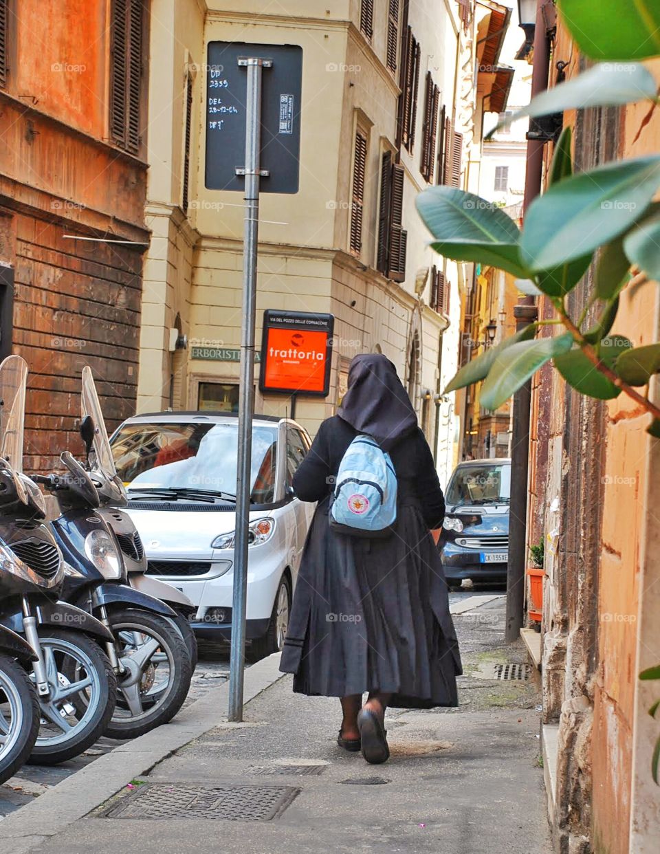 Nun on the run. A nun with a backpack walks down a Roman street lined with motorcycles