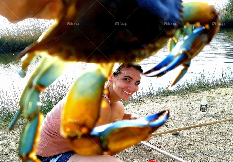 beautiful woman with a cute surprised look between the claws of a blue crab caught off of the Gulf of Mexico near Bridge City Texas United States of America 2018