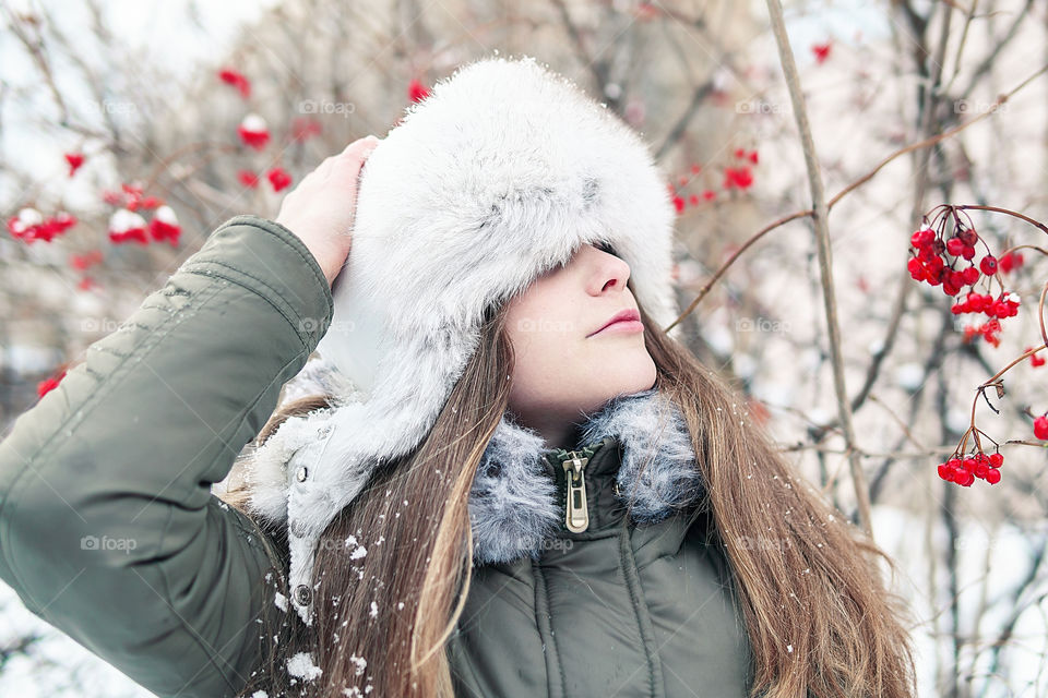 Winter is here, red winter berries and girl in the warm winter hat