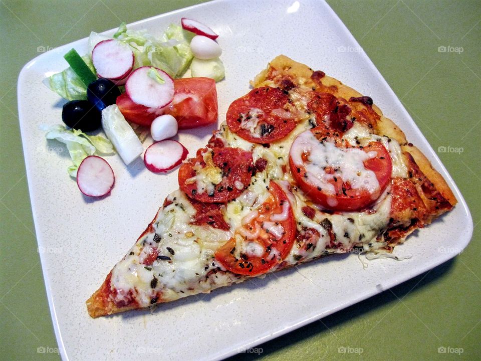 Slice of pizza and tossed salad on white plate