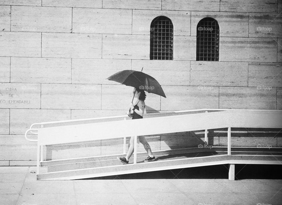 Girl walking with an umbrella to protect her from the sun 