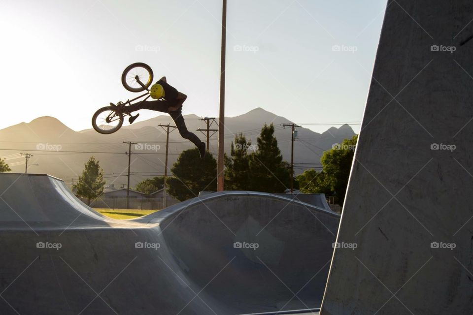 Sunbeams. Bmx rider does trick with sun shining on him