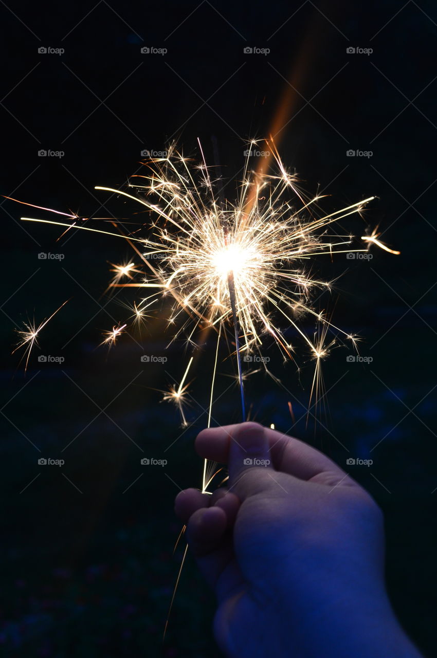 Hand holding a sparkler on black background