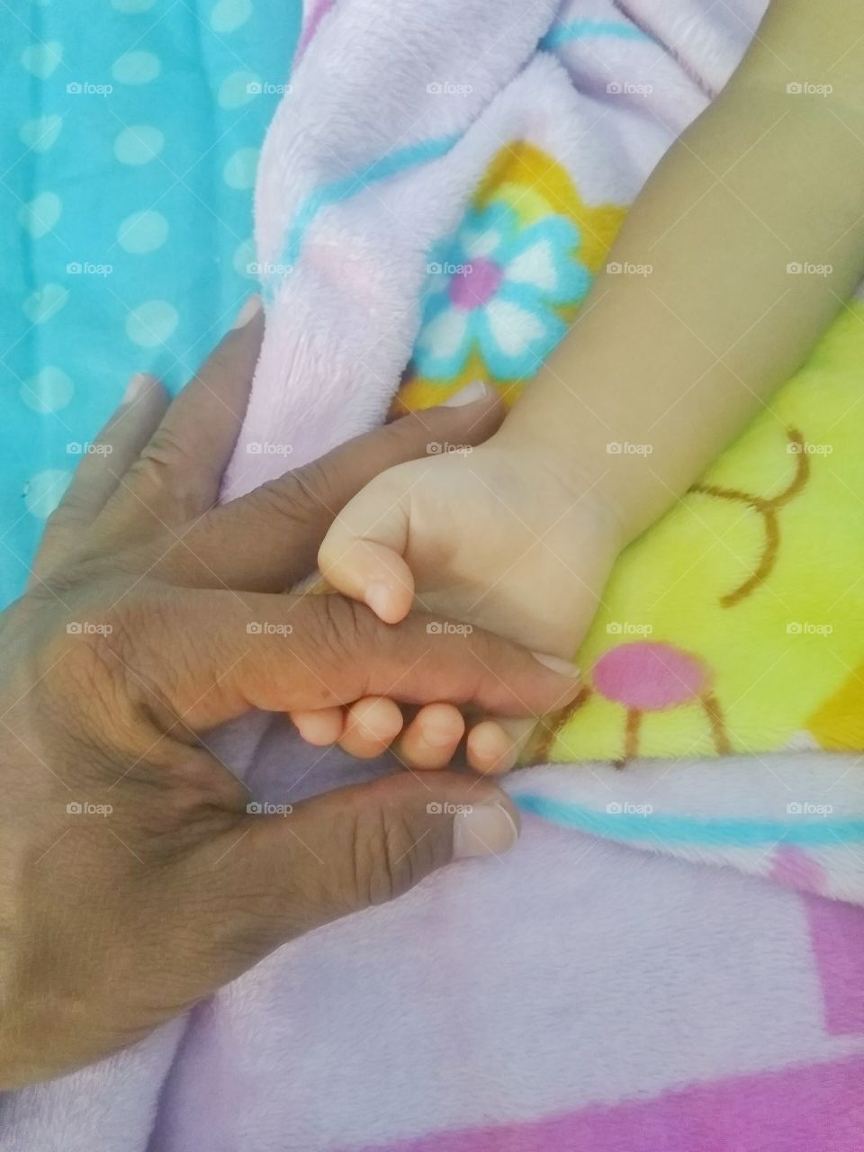 Baby's hand holding father's finger while sleeping deeply.