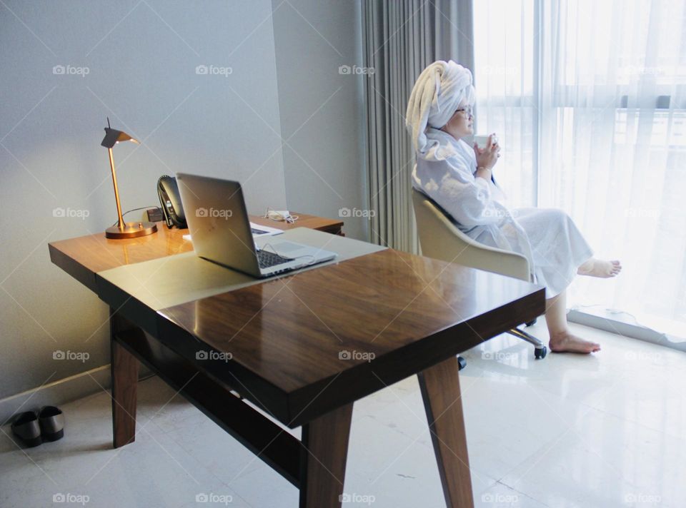 Starting a sunny morning while drinking a glass of coffee in front of the apartment window.