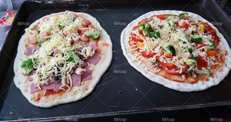 Artisanal pizzas with tomato and broccoli and bell pepper and mozzarella and ham and shrimp being prepared for the oven