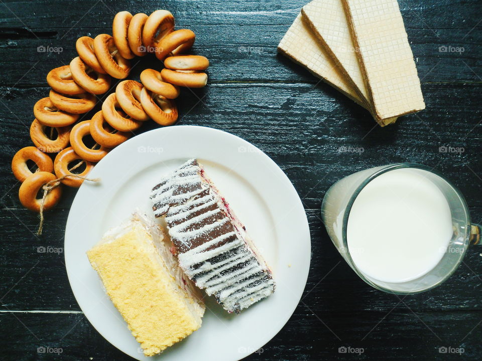 cakes, a cup of milk, bagels and waffles on a black background