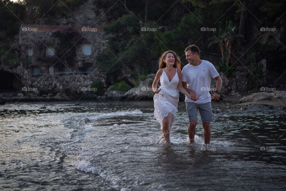 Happy couple is running on the sea shore