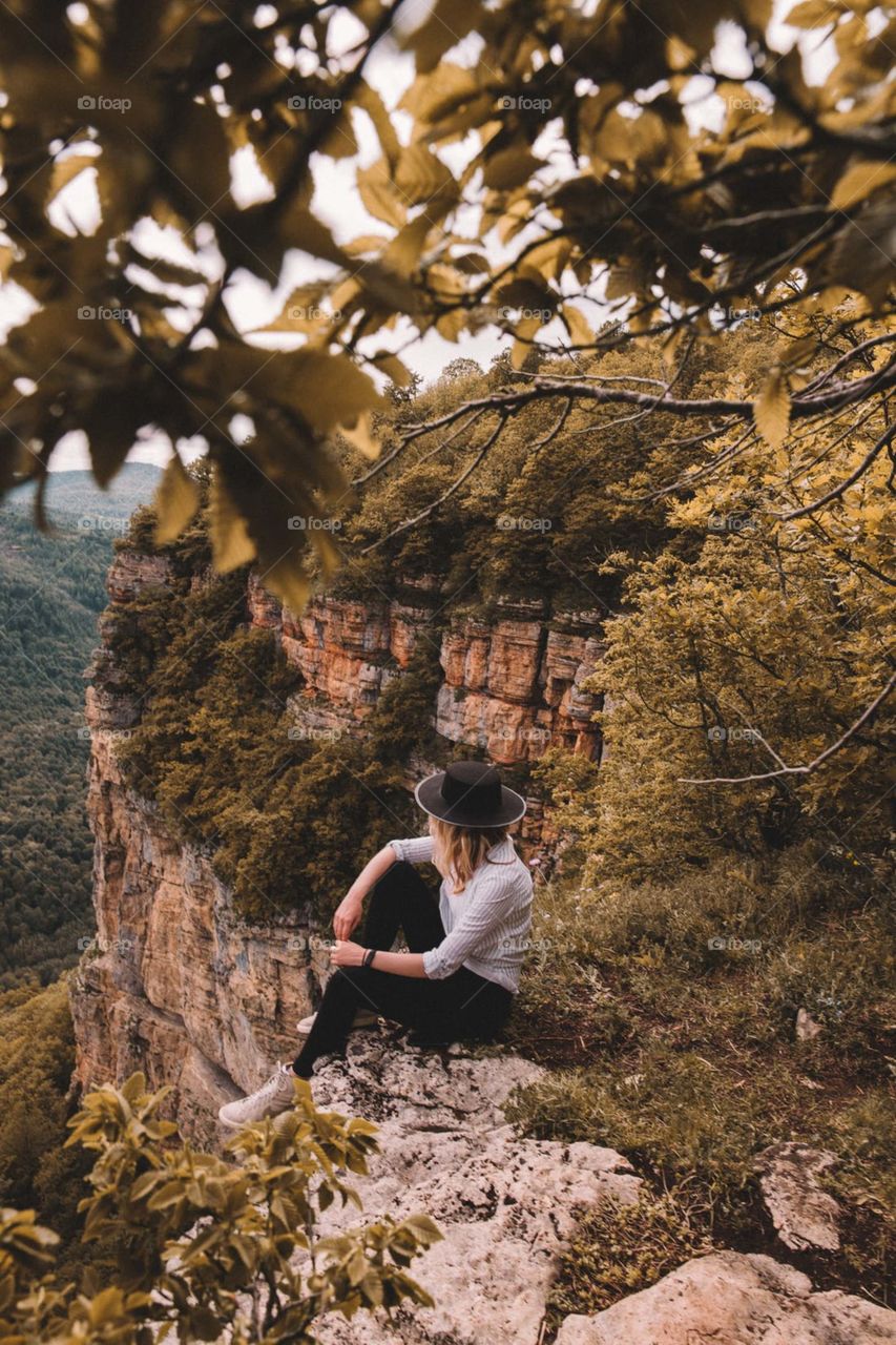 woman sitting on mountain cliff