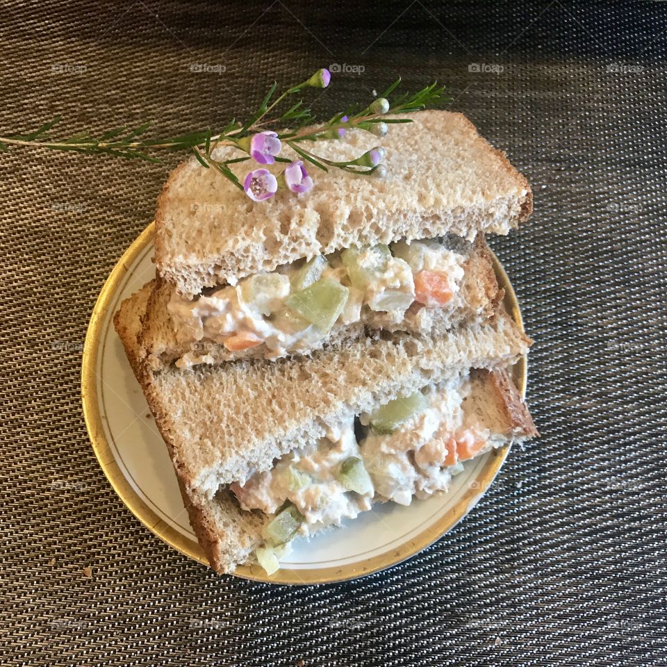 Toasted Tunafish salad sandwich on white bread with celery and peppers garnished with a dainty violet flower on top. USA, America 