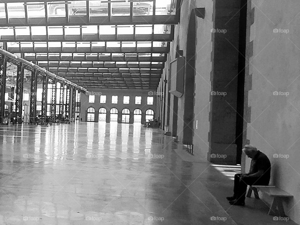 A lonely man sitting on a bench in a huge place. Loneliness, waiting or rest ?
Former industrial site renovated and rehabilitated into a multicultural place "les ateliers des Capucins" in Brest, Brittany, France.