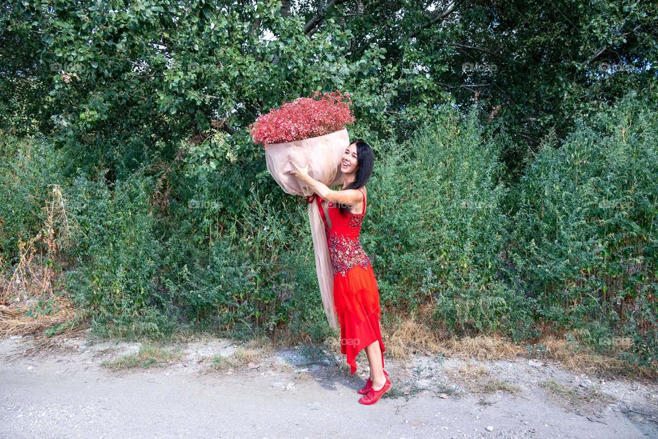 Woman Dances with a Large Bouquet of Red Flowers