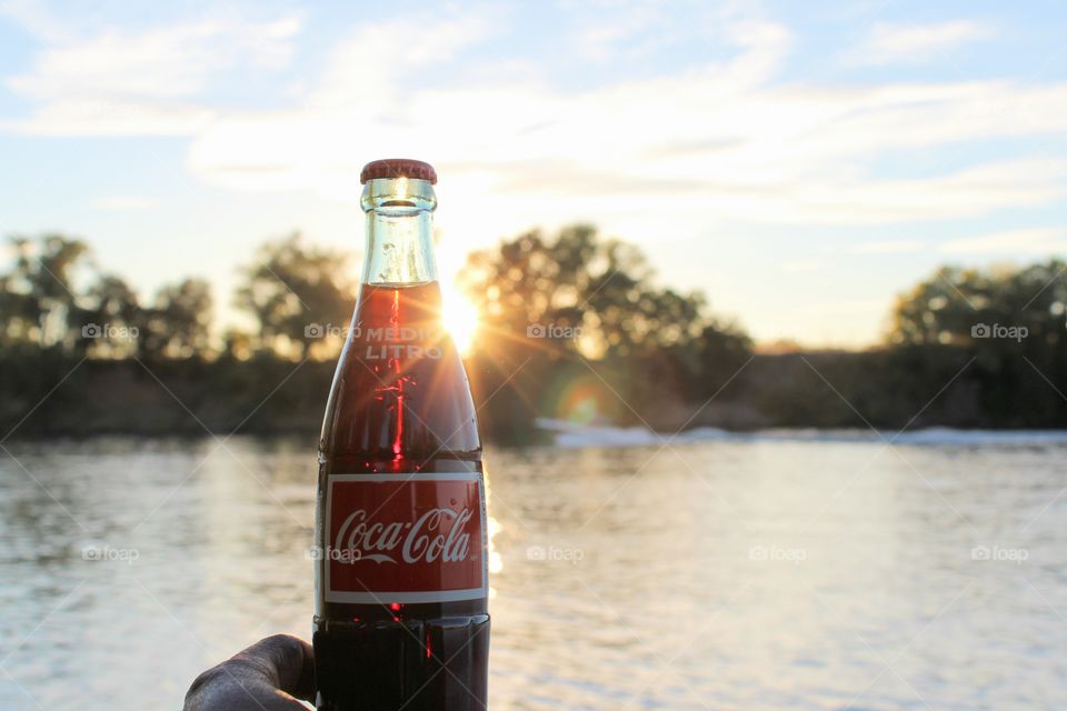 watching the sunset while holding a bottle of Coca-Cola