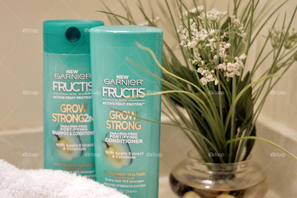 Garnier shampoo and conditioner on a countertop with a white towel and a plant in the background