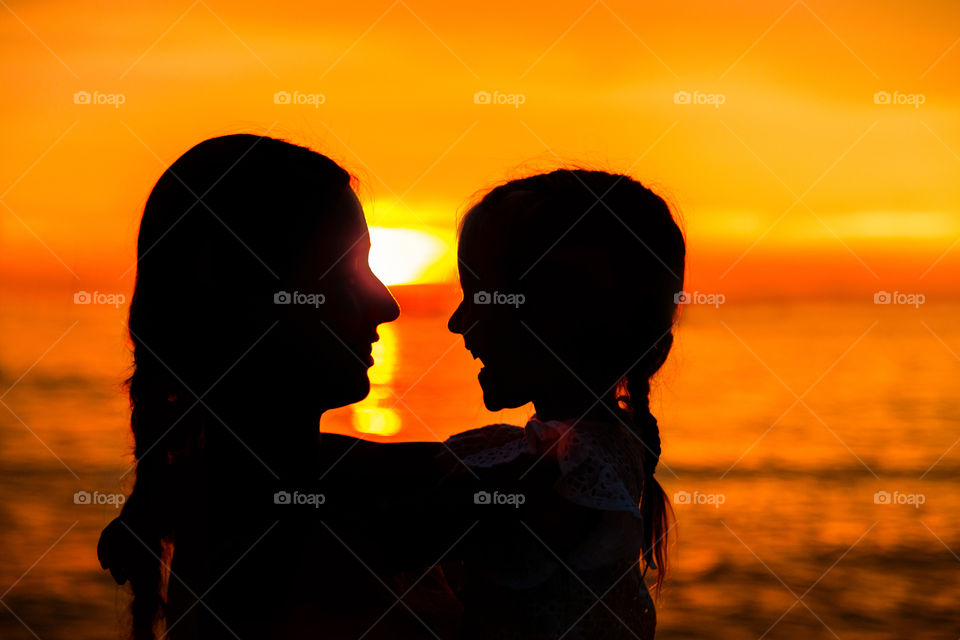 Silhouette of mother and little daughter on the sea