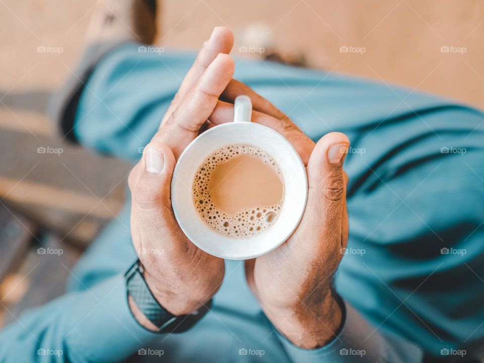 View from above of a man holding a cup of hot chai tea in Islamabad, Pakistan