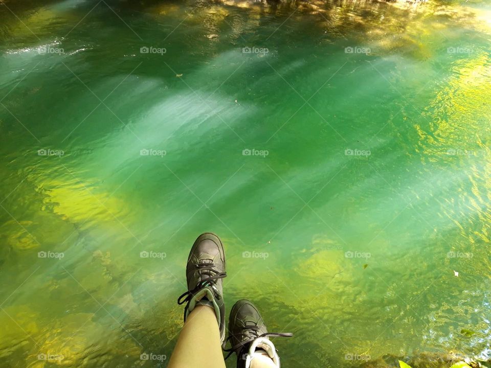 The image shows a green lake, likely colored by mineral deposits or algae, surrounded by natural vegetation, creating a striking landscape.
