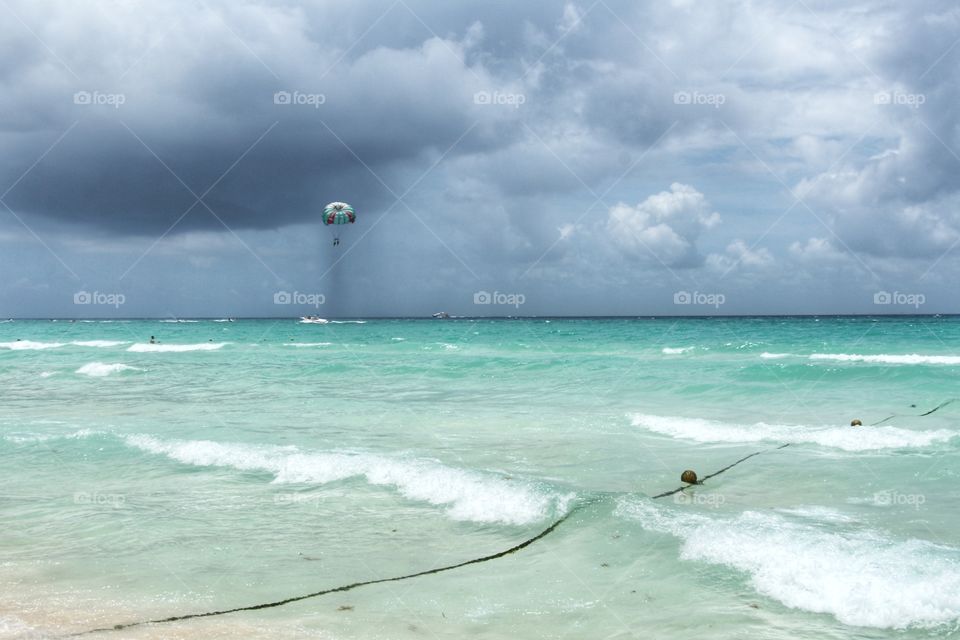 Paragliding under caribbean sea with storm clouds in the horizon