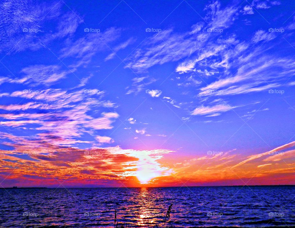 
The big orange ball slowly going down and down and it sets into the horizon making the  blue clouds and sky absolutely stunning. 