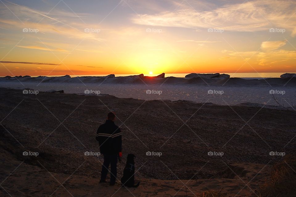 Wintertime in Michigan! A man and his dog watching the sunset 