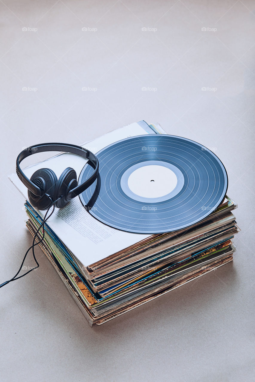 Stack of many black vinyl records, headphones on the top of stack. Candid people, real moments, authentic situations