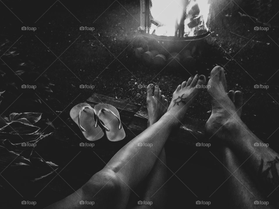 Black and white photograph of a couple relaxing by a fire with their feet up.